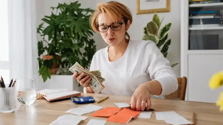 A person reviewing cash and receipts beside a calculator and notebook