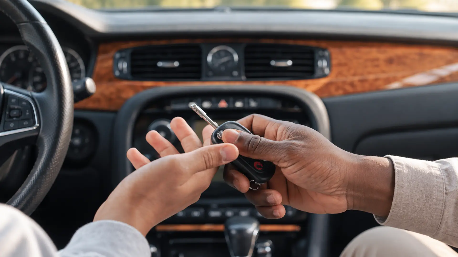 Two hands exchanging a car key inside a vehicle